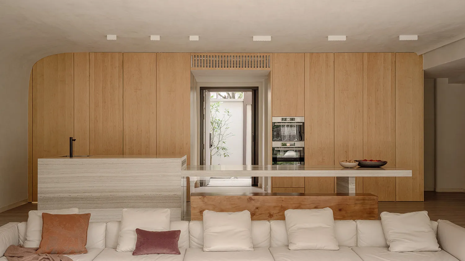 A modern interior with wooden panels, white couch, and white countertop.