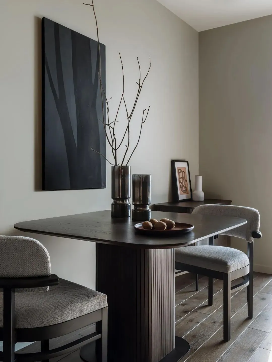 A minimalist dining room featuring a wooden table, chairs, and decorative elements.