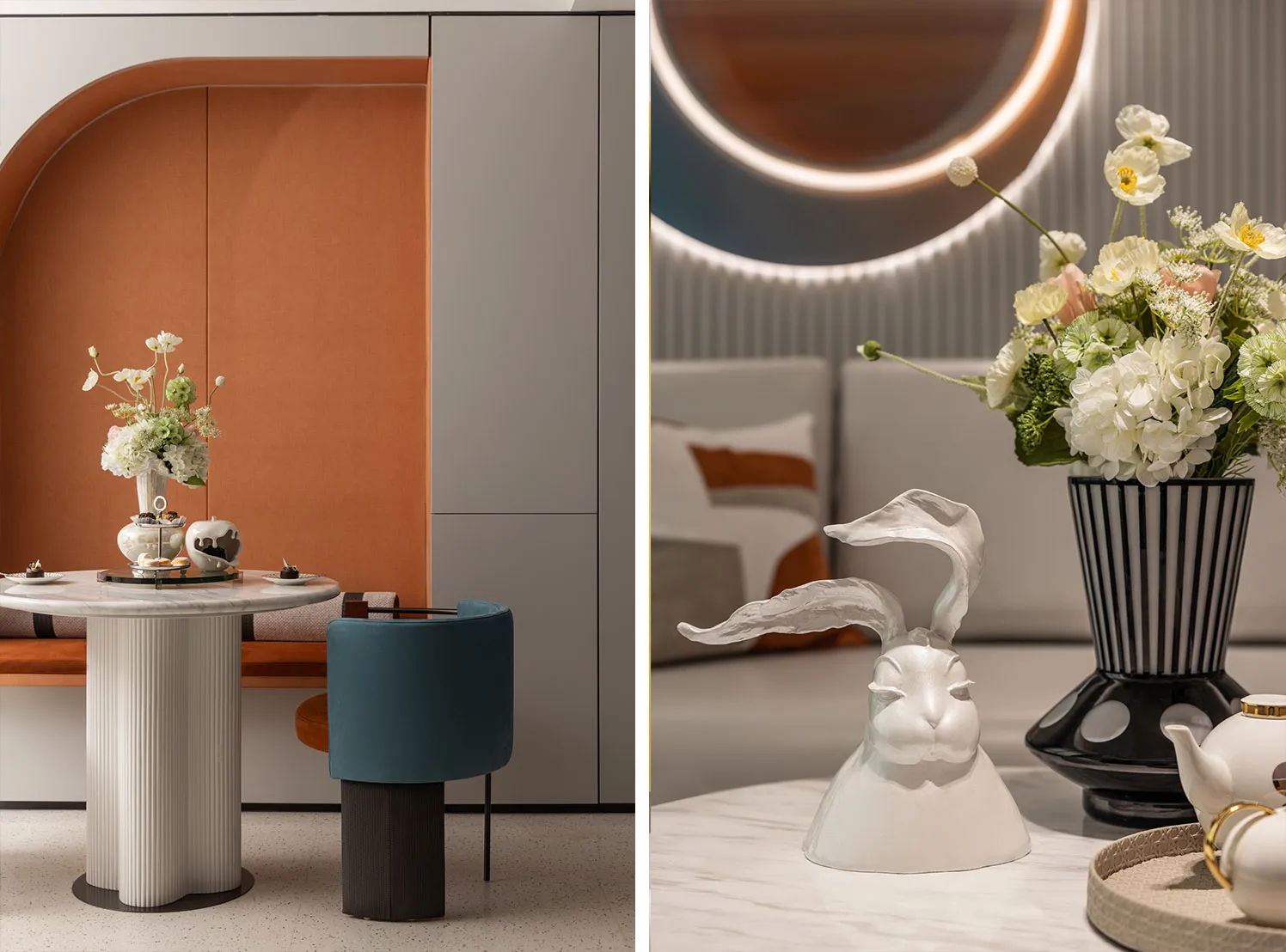 A modern living room featuring a textured marble table with a blue cushioned stool and a circular mirror with backlit lightin
