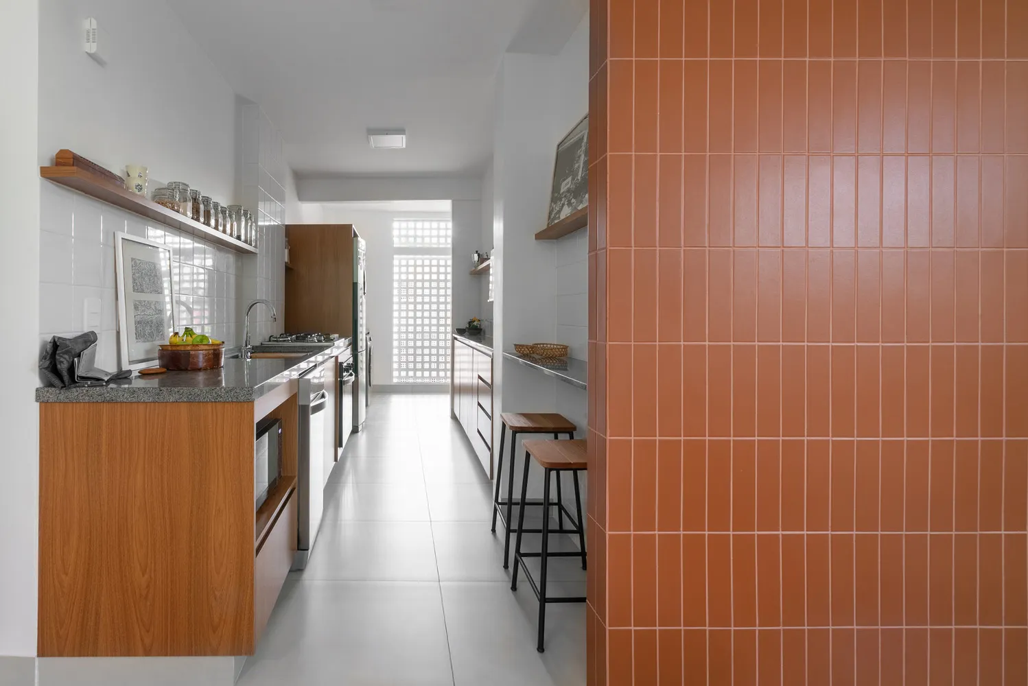 Modern minimalist kitchen with white and wood finishes and terracotta tile backsplash.