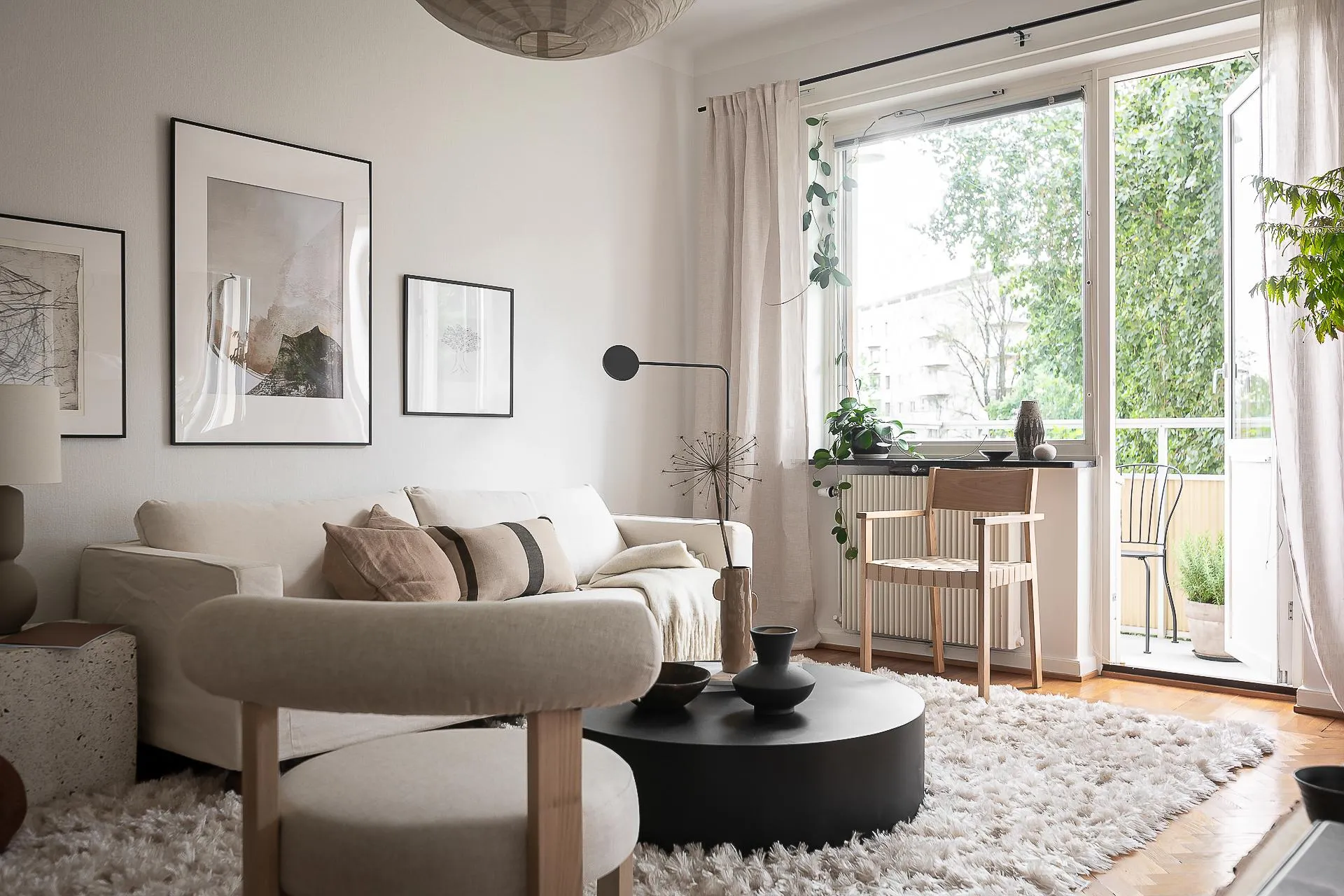 A minimalist living room with white fabric furniture and a black coffee table.