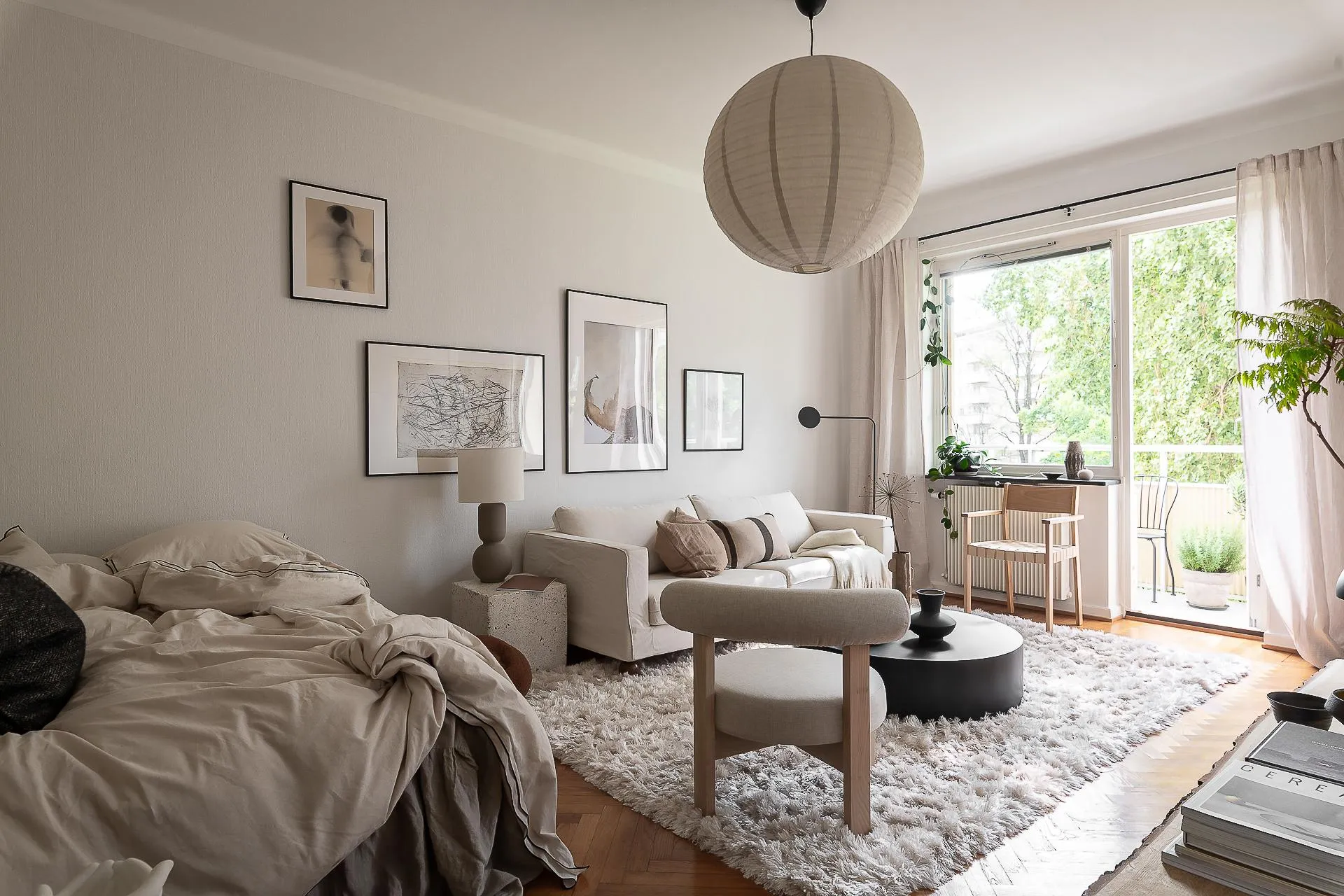 A modern minimalist living room with a white sofa, wooden chair, concrete cube, and white rug.