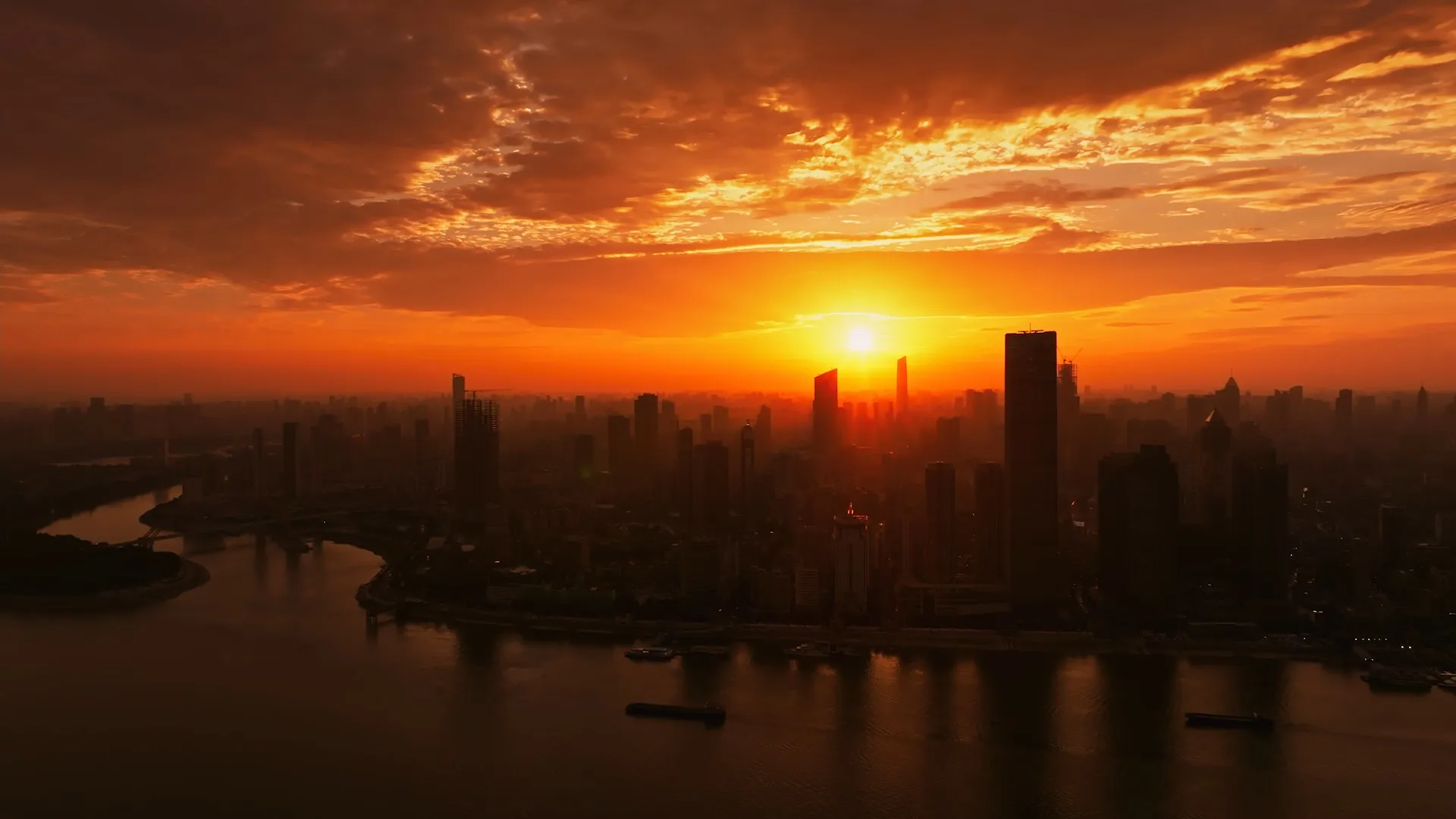 Aerial view of a city skyline at sunset with skyscrapers and a river.