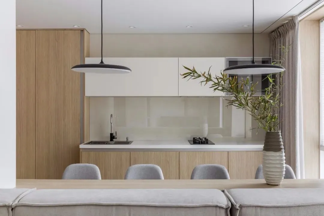 Contemporary residential kitchen featuring light wood cabinets and glass countertops.
