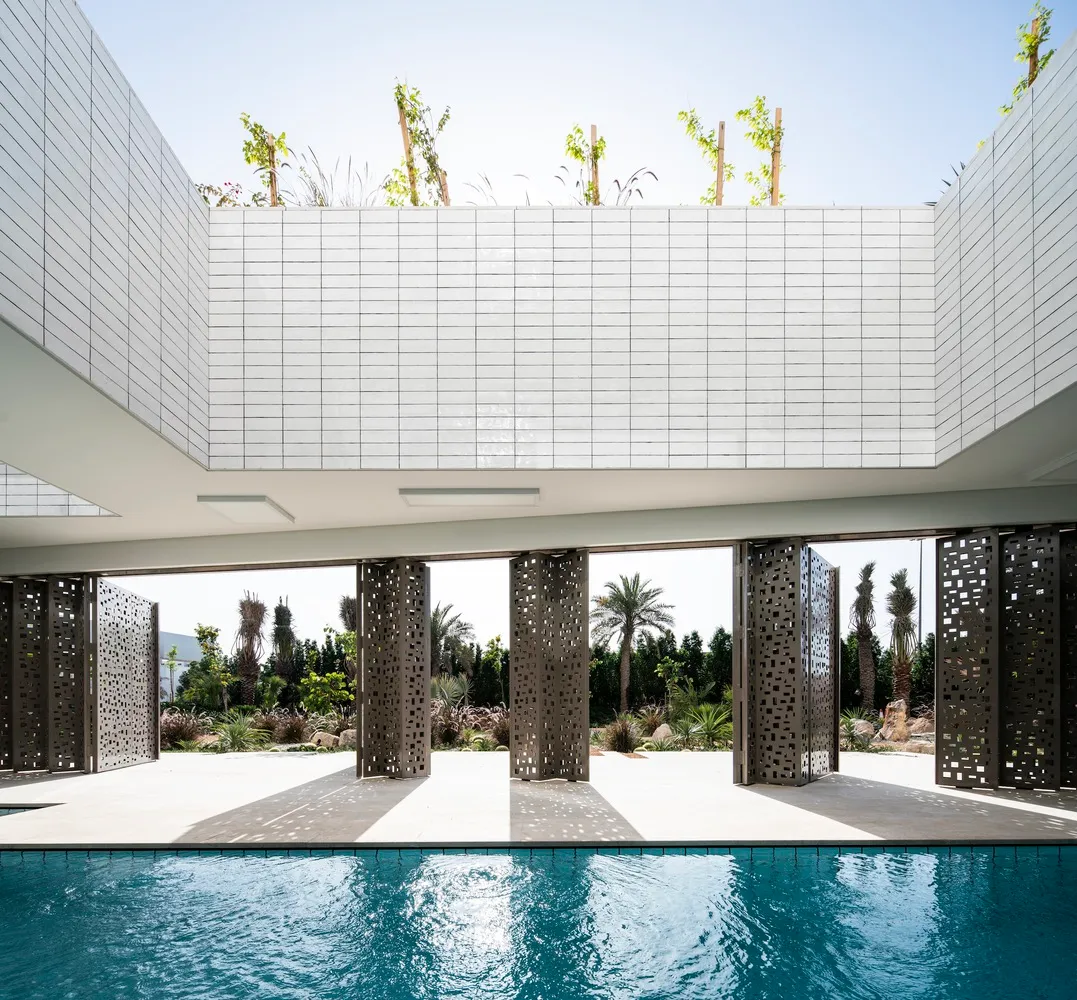 一座採用白色建材與金屬磚的現代泳池小屋