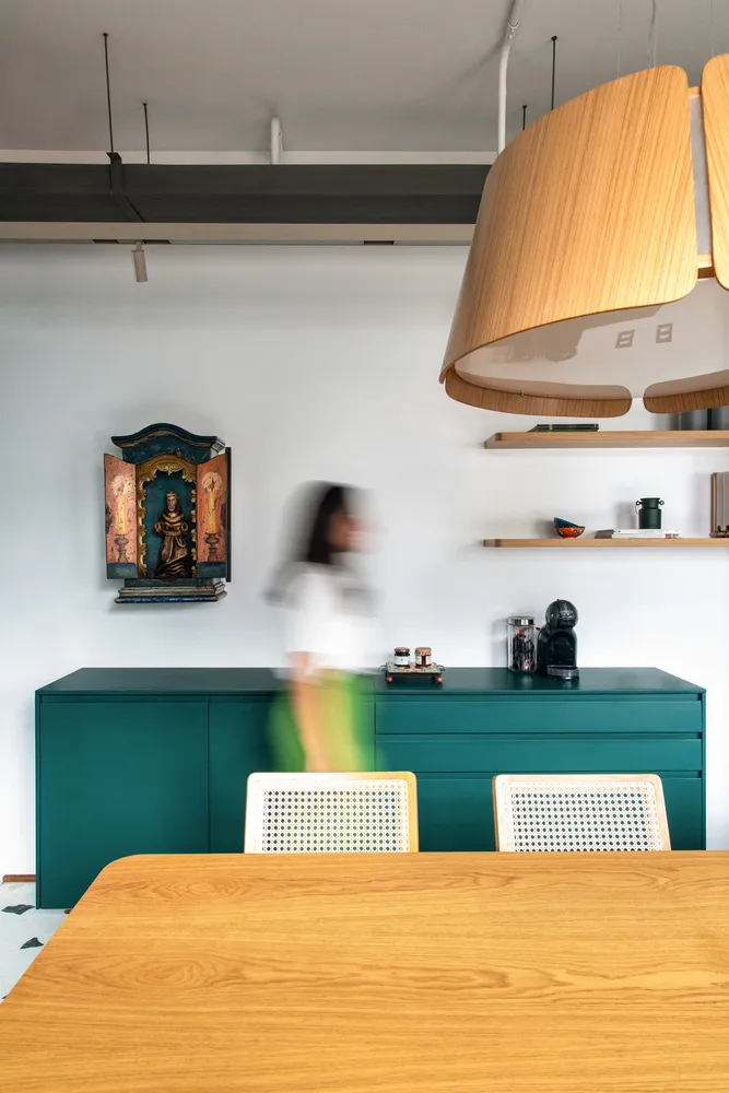 Modern kitchen with teal cabinets, wooden table, and hanging light fixture