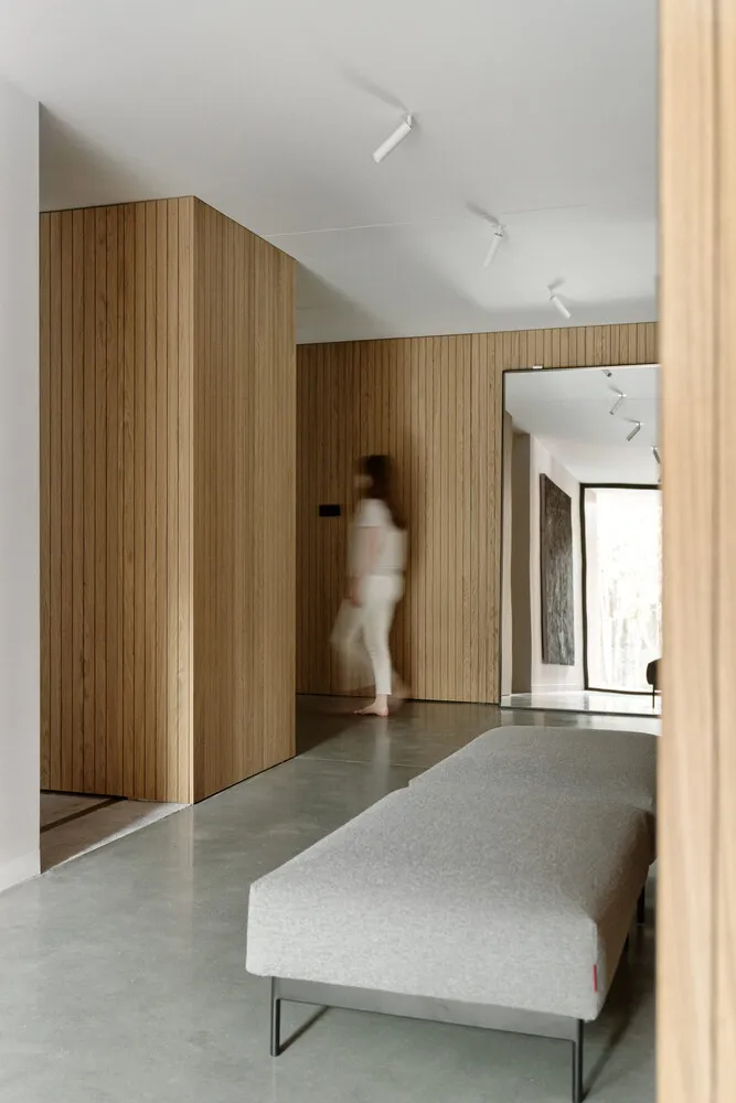 A modern residential interior featuring wooden walls, concrete flooring, and metal accents.