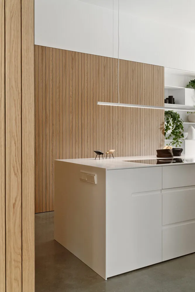 A modern residential kitchen with wooden walls and white cabinetry.