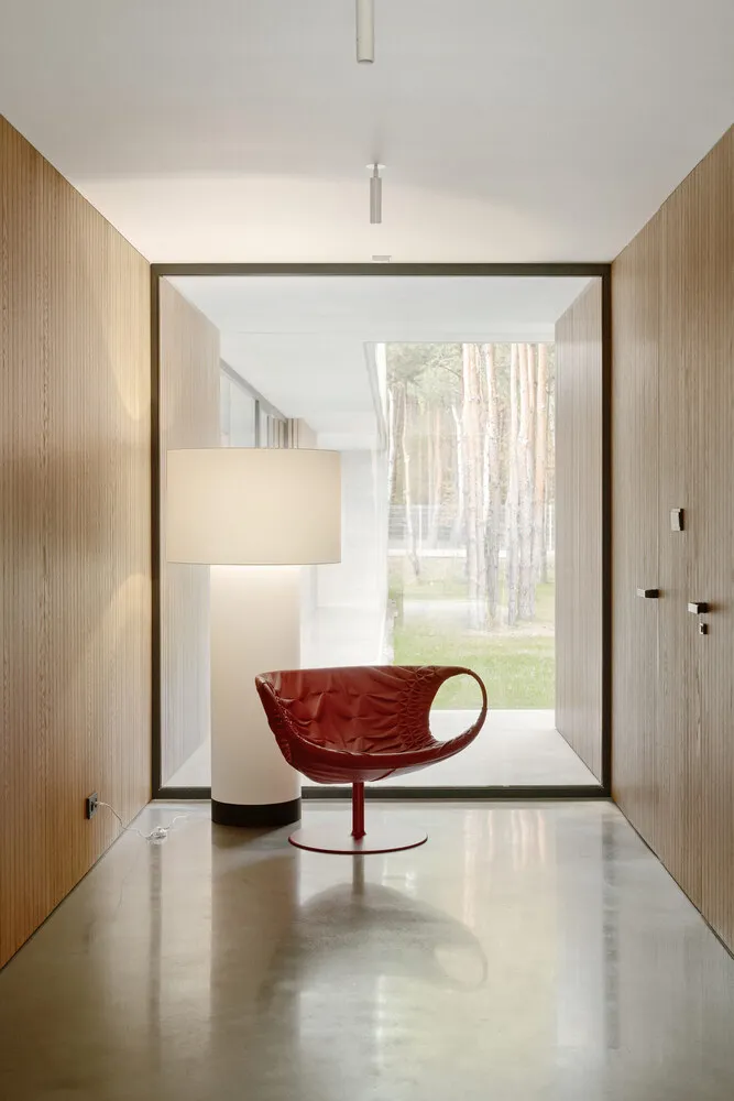 A modern residential lounge featuring a red leather armchair and a white floor lamp.