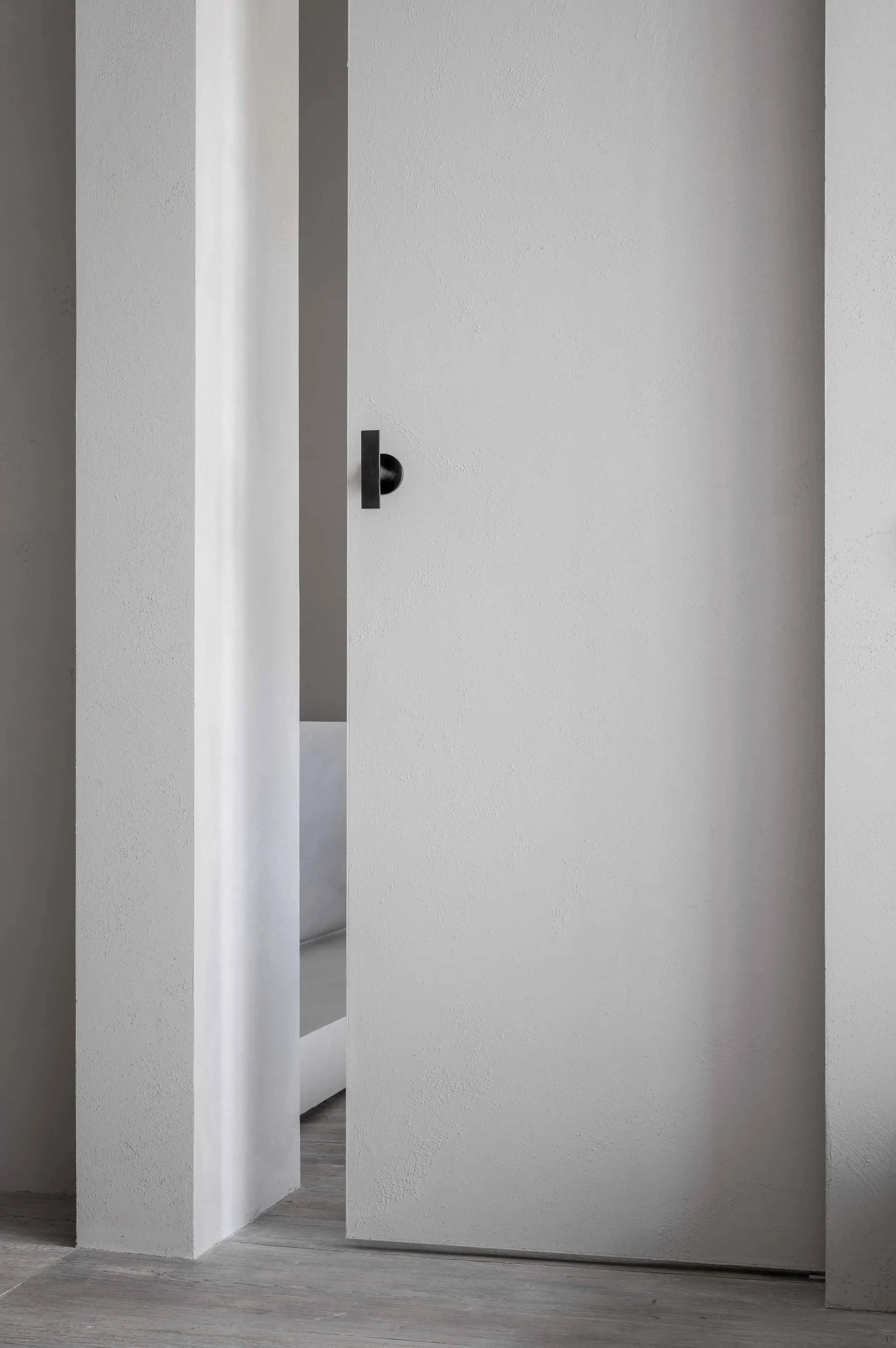 A minimalist doorway with a concrete wall and minimalist door handle.