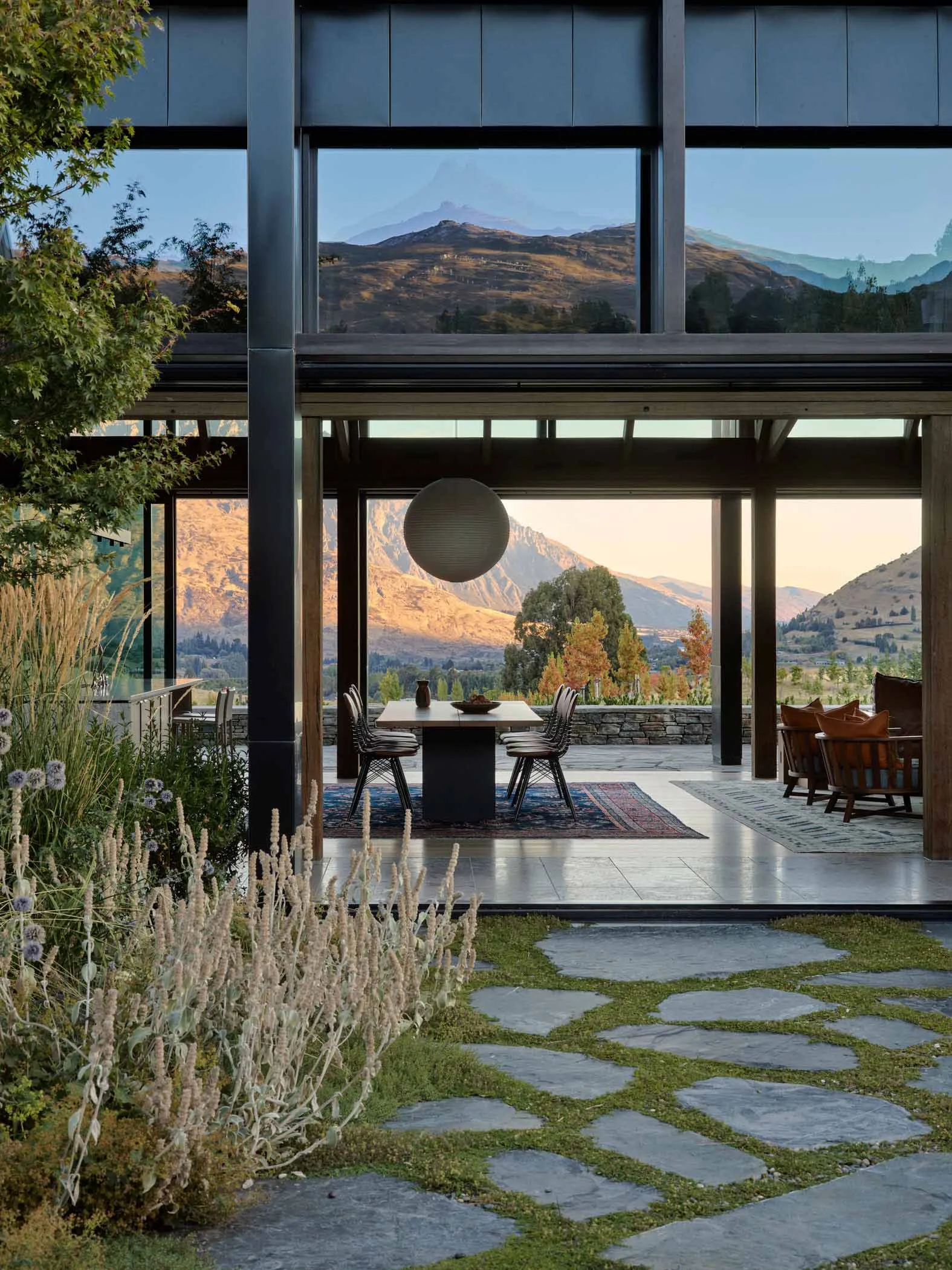 Modern residential exterior with concrete flooring and walls, featuring an open living area with large windows overlooking mo