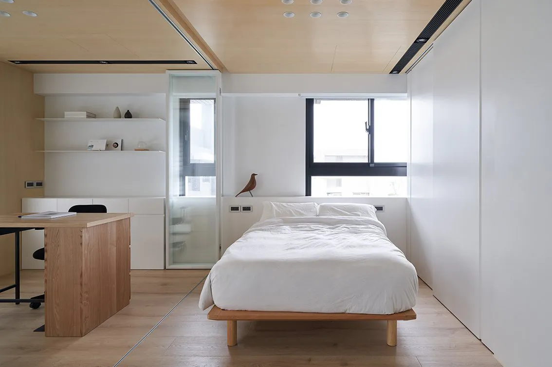 A modern bedroom featuring white furniture and wooden details.