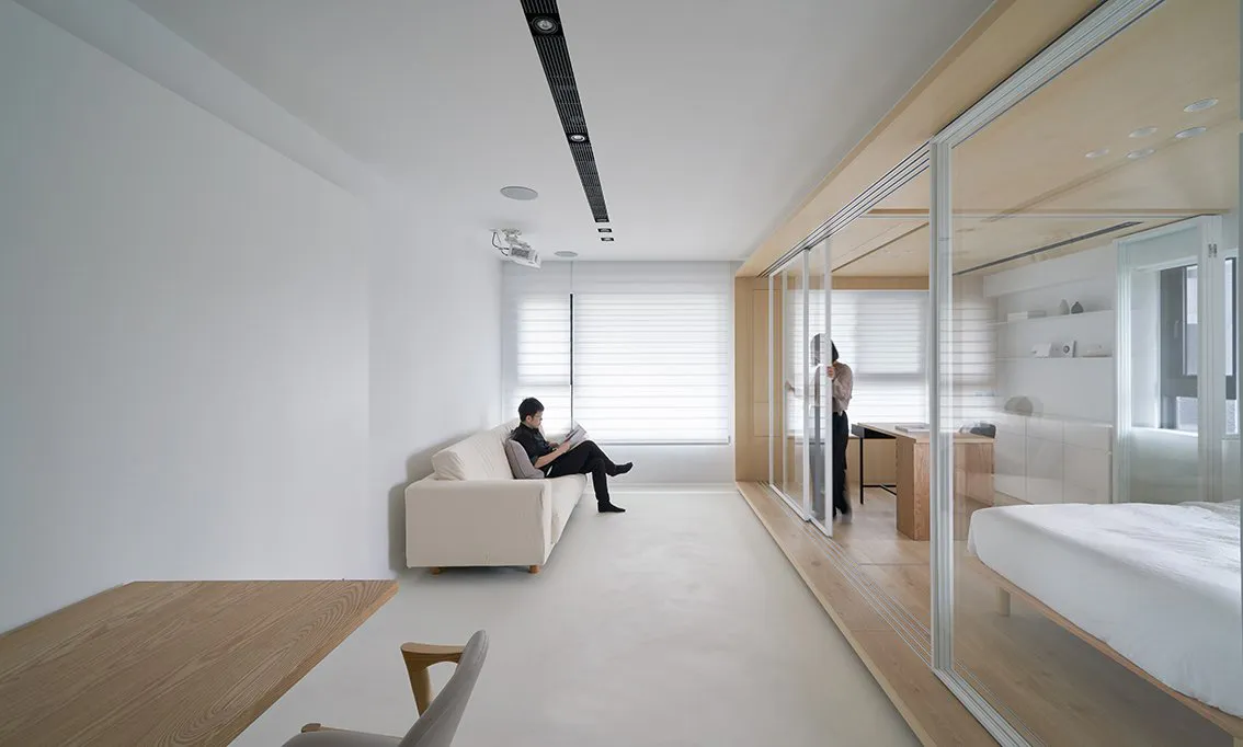 Modern minimalist living room with white furniture, wood accents, and white walls.