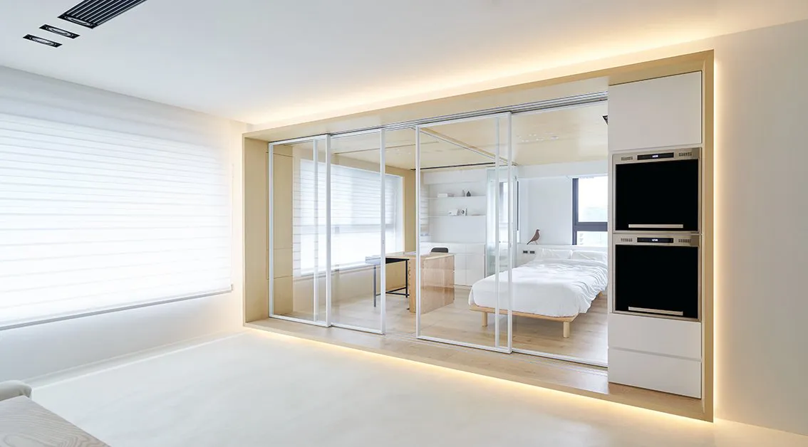 A modern minimalist bedroom featuring a glass partition wall for a unique design.
