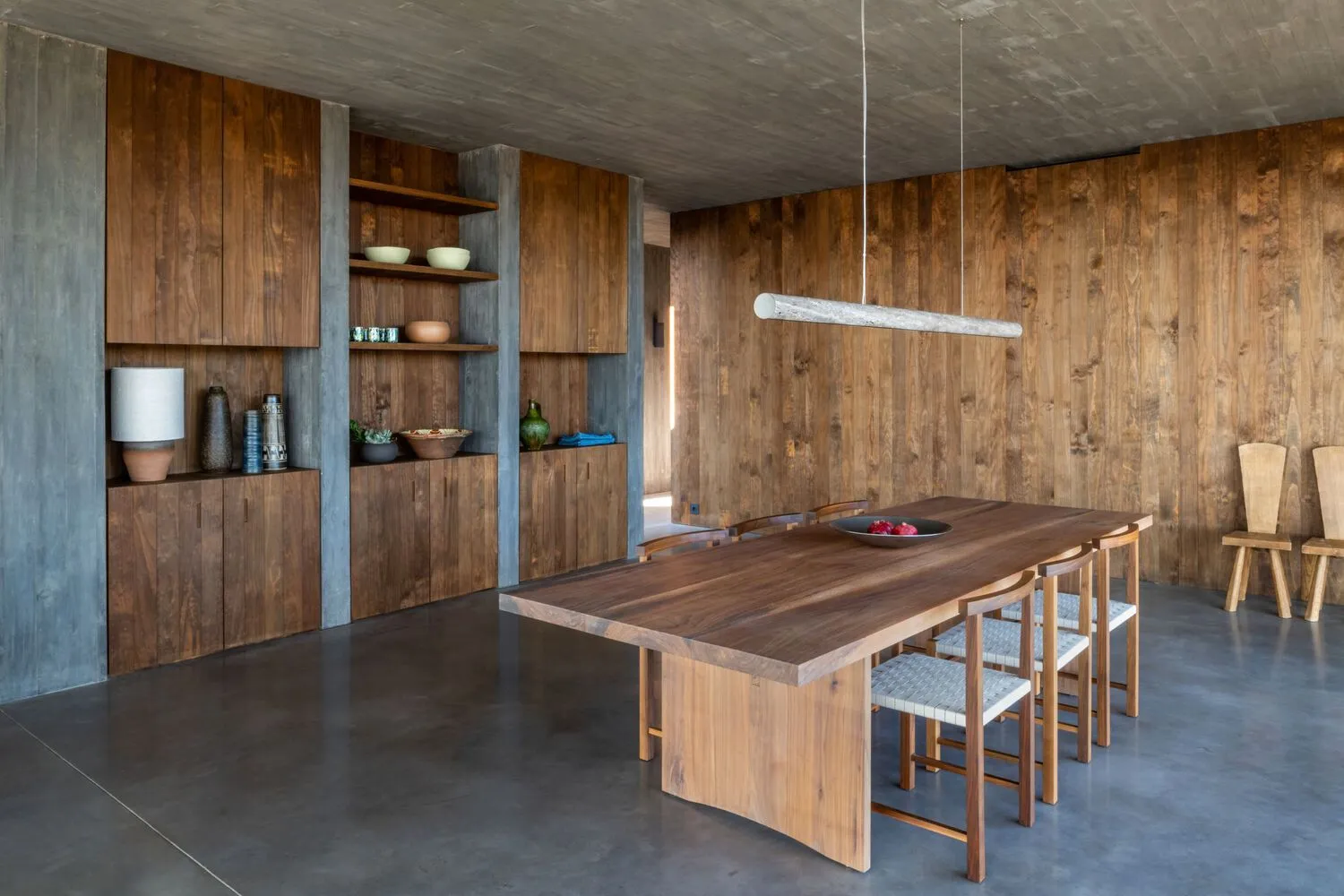 An industrial residential dining room with wooden furniture and concrete walls.
