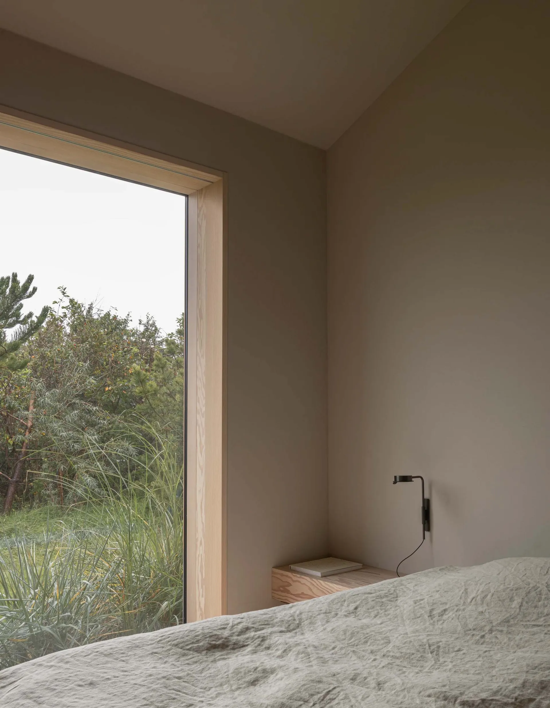 A minimalist bedroom with natural wood accents and grey fabric bedding