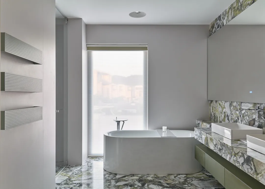 Modern industrial bathroom featuring a white freestanding tub with a marble floor and countertop.