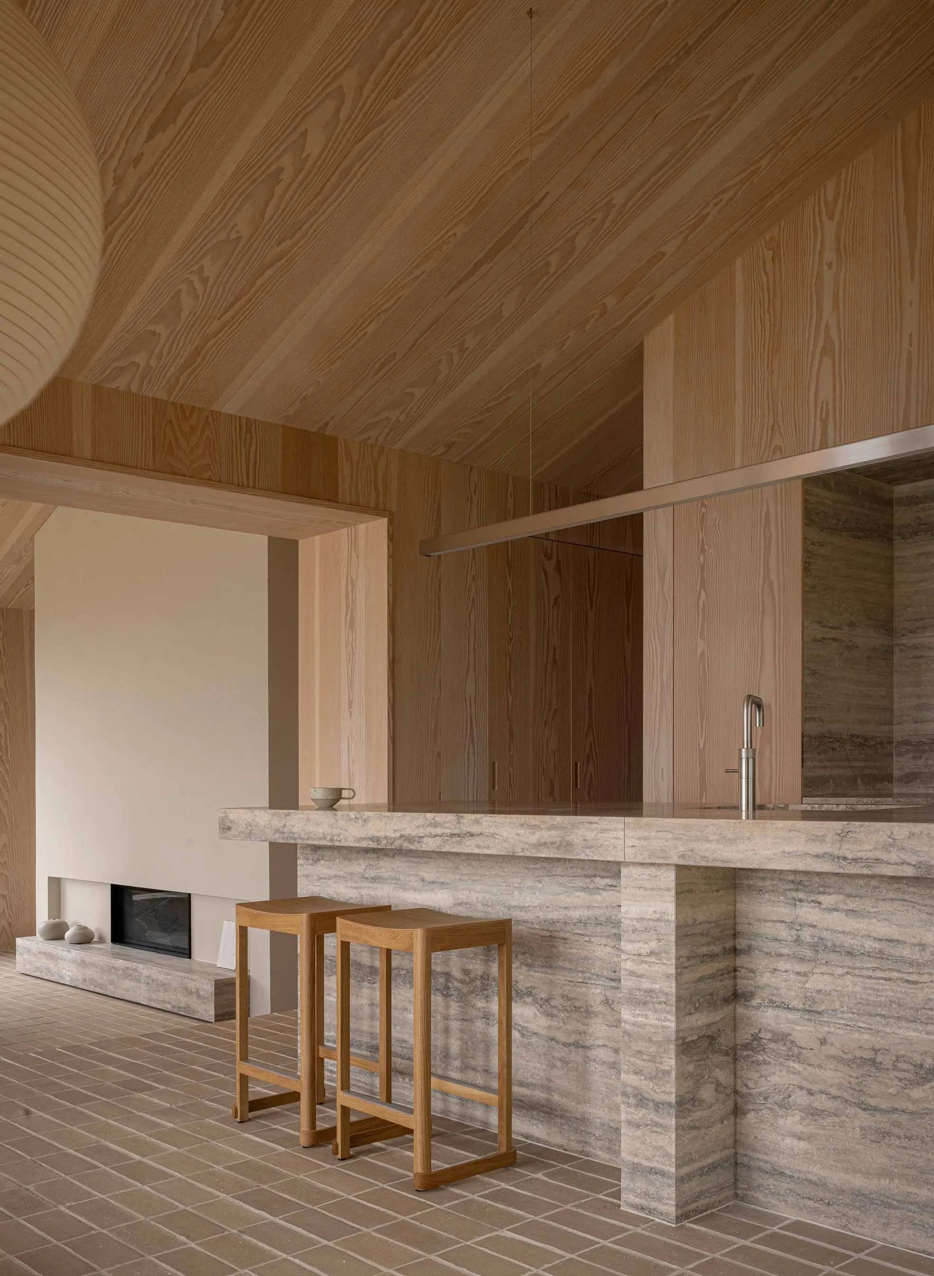 A minimalist kitchen with a stone countertop and wooden stools.