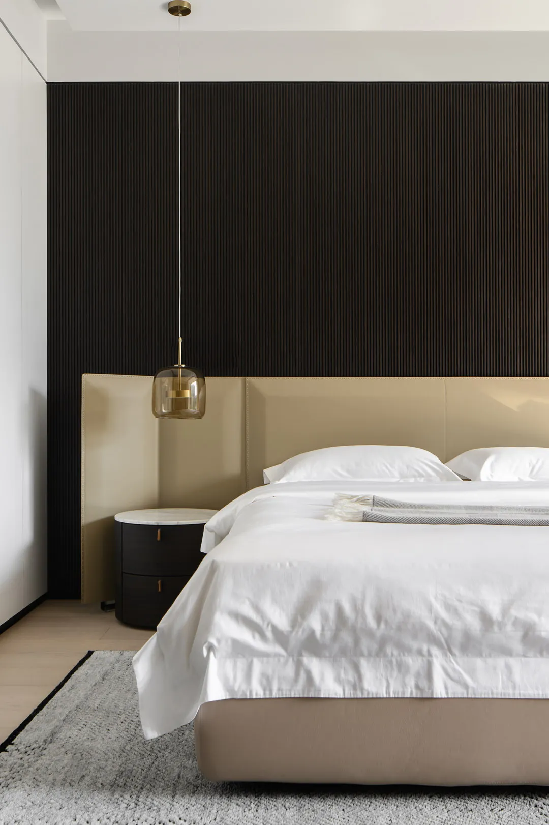 一間現代簡約臥室,配有米色床頭板、白色的床品,以及深色木質特色牆。