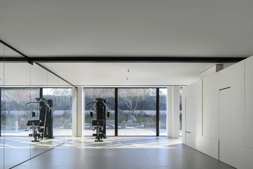 Modern minimalist fitness center with metal windows and exercise equipment.