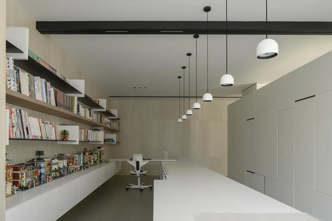 A modern minimalist office with white materials and a sleek, white desk.