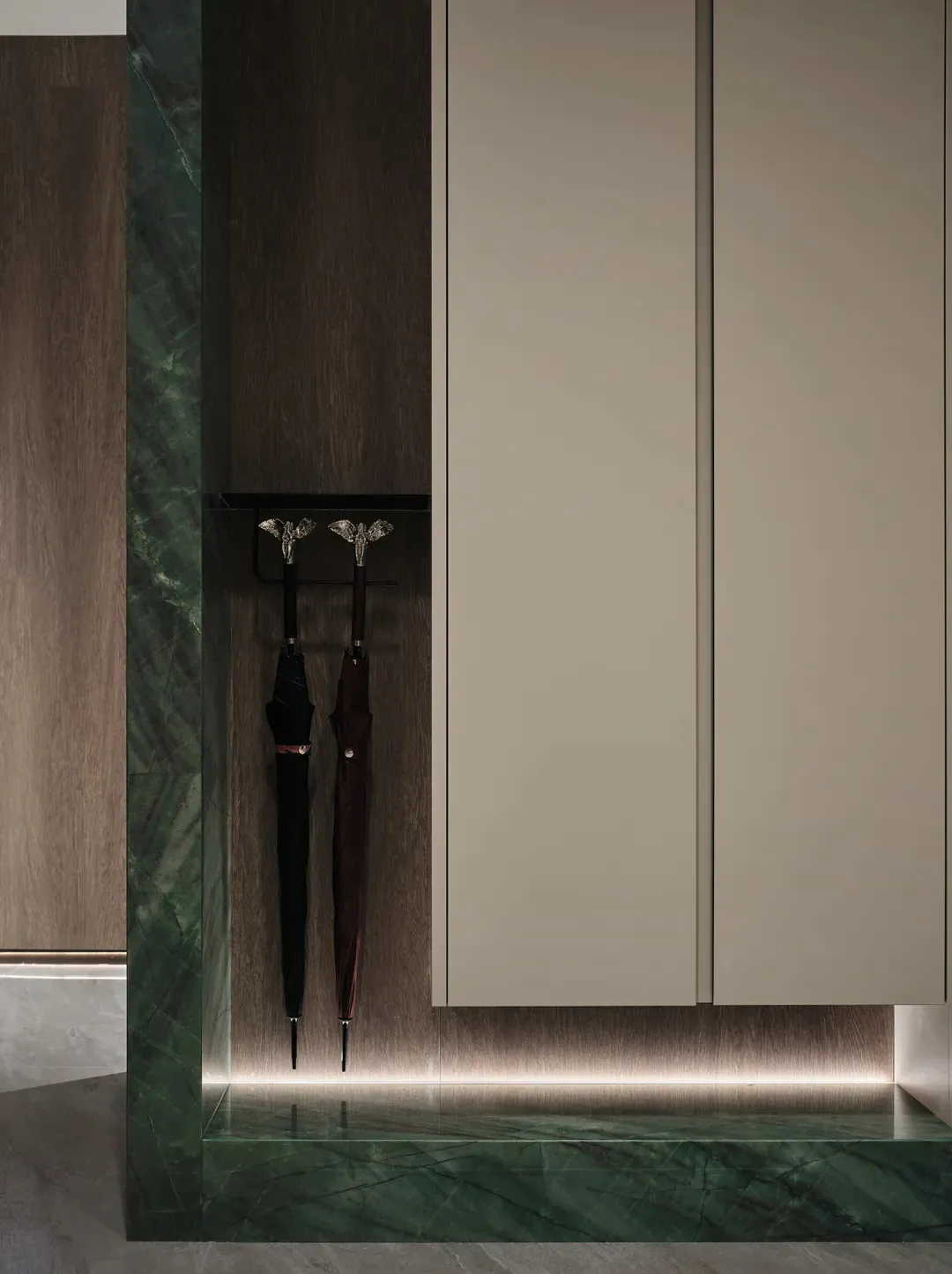 Modern entryway featuring green marble flooring and a wall-mounted umbrella stand.