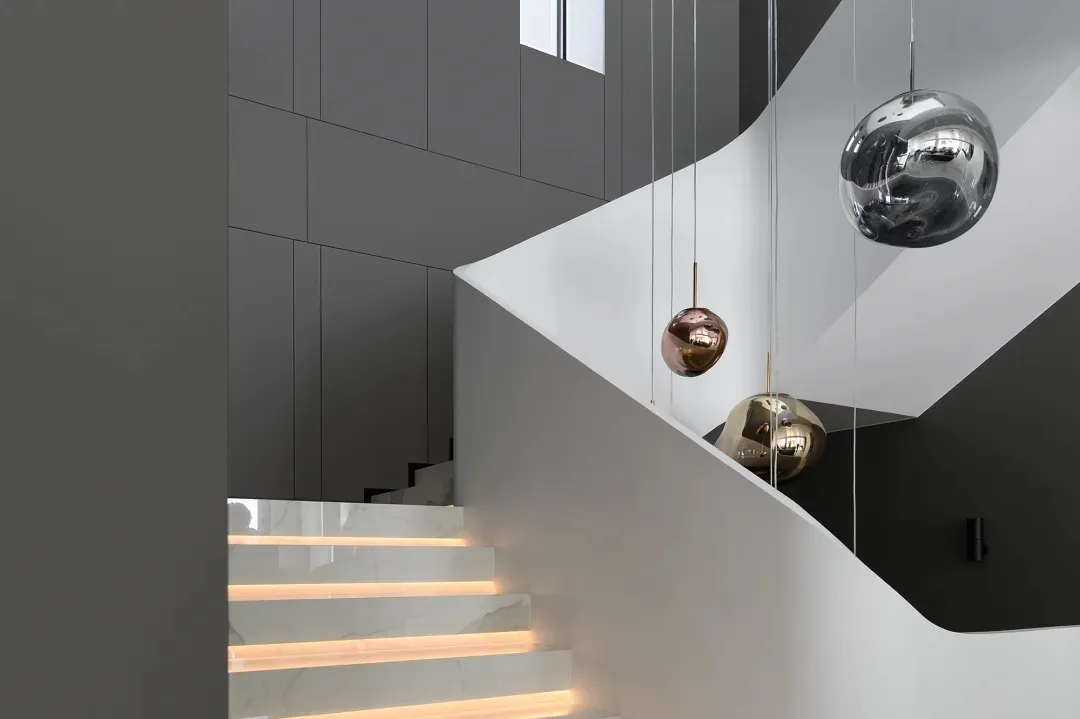 Modern, white marble staircase with metallic accents and illuminated steps.