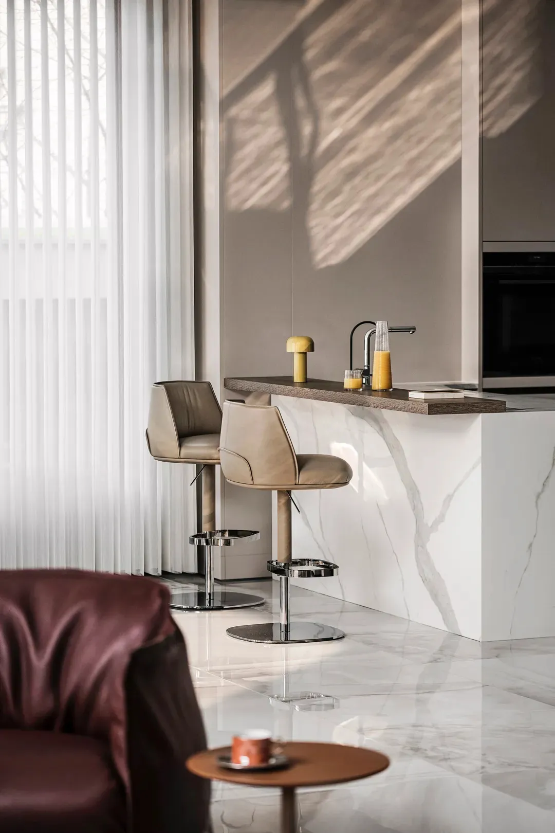 Image of a modern minimalist kitchen featuring marble countertops and bar stools.