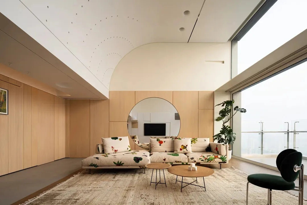 Contemporary living room with minimalist design featuring wood paneling, glass windows, and a cozy sofa with floral print pil