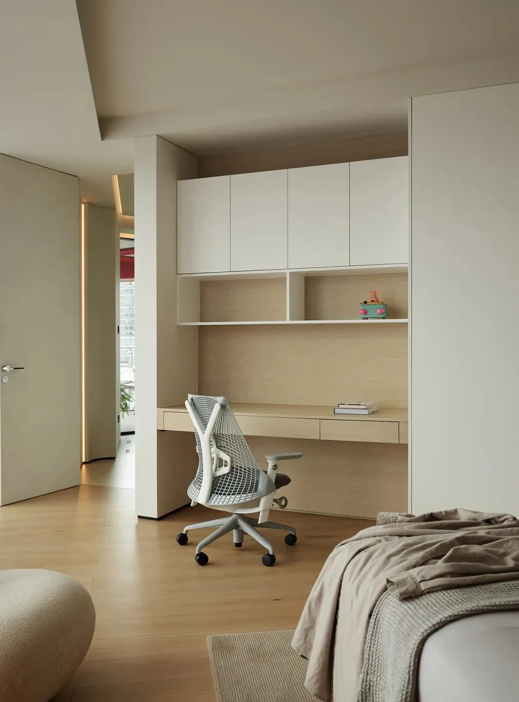 Modern minimalist master bedroom featuring a white desk with a mesh office chair, beige flooring, and light-colored wood cabi