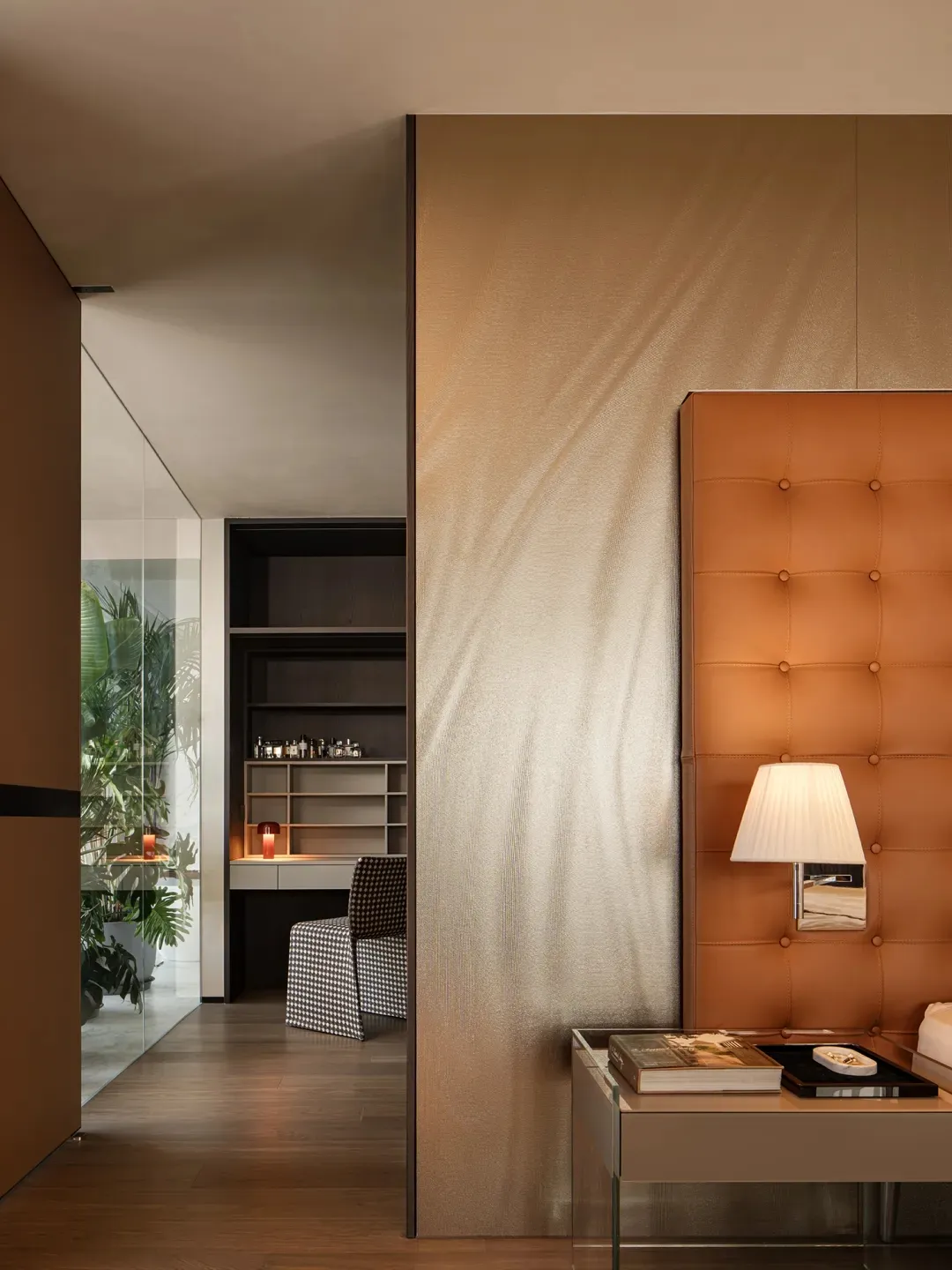 Modern bedroom interior with a brown leather upholstered headboard, wooden flooring, and a glass partition.
