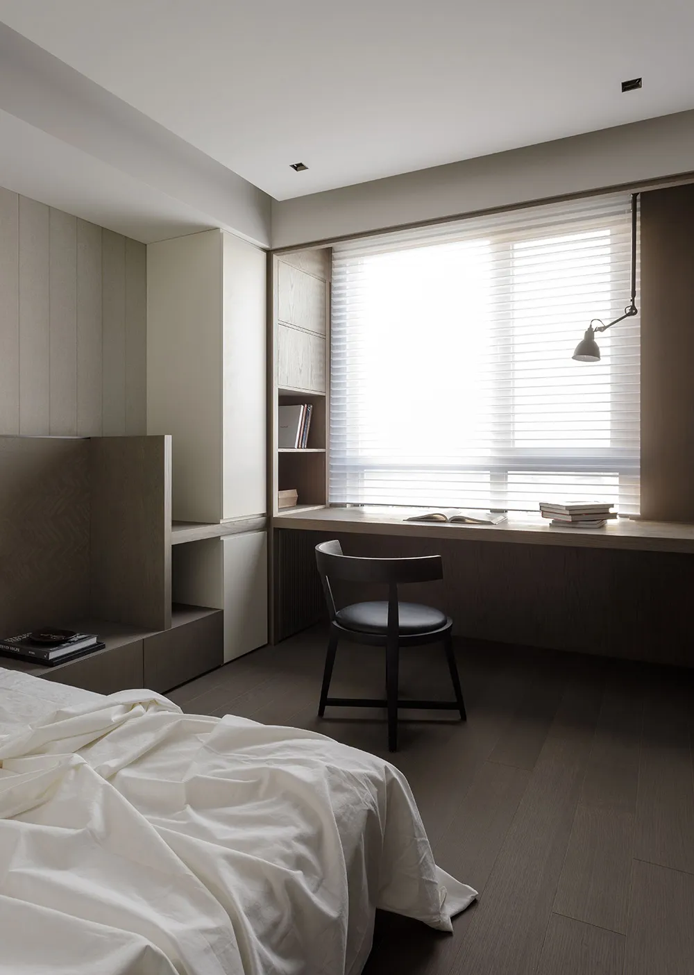 A modern minimalist bedroom with a window, wooden furniture, and white bedding.