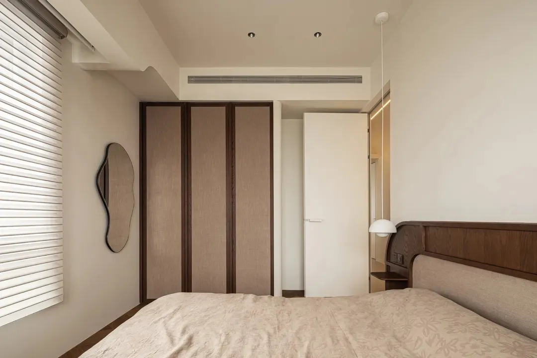Modern bedroom with wood-textured furniture and light-colored bedding.