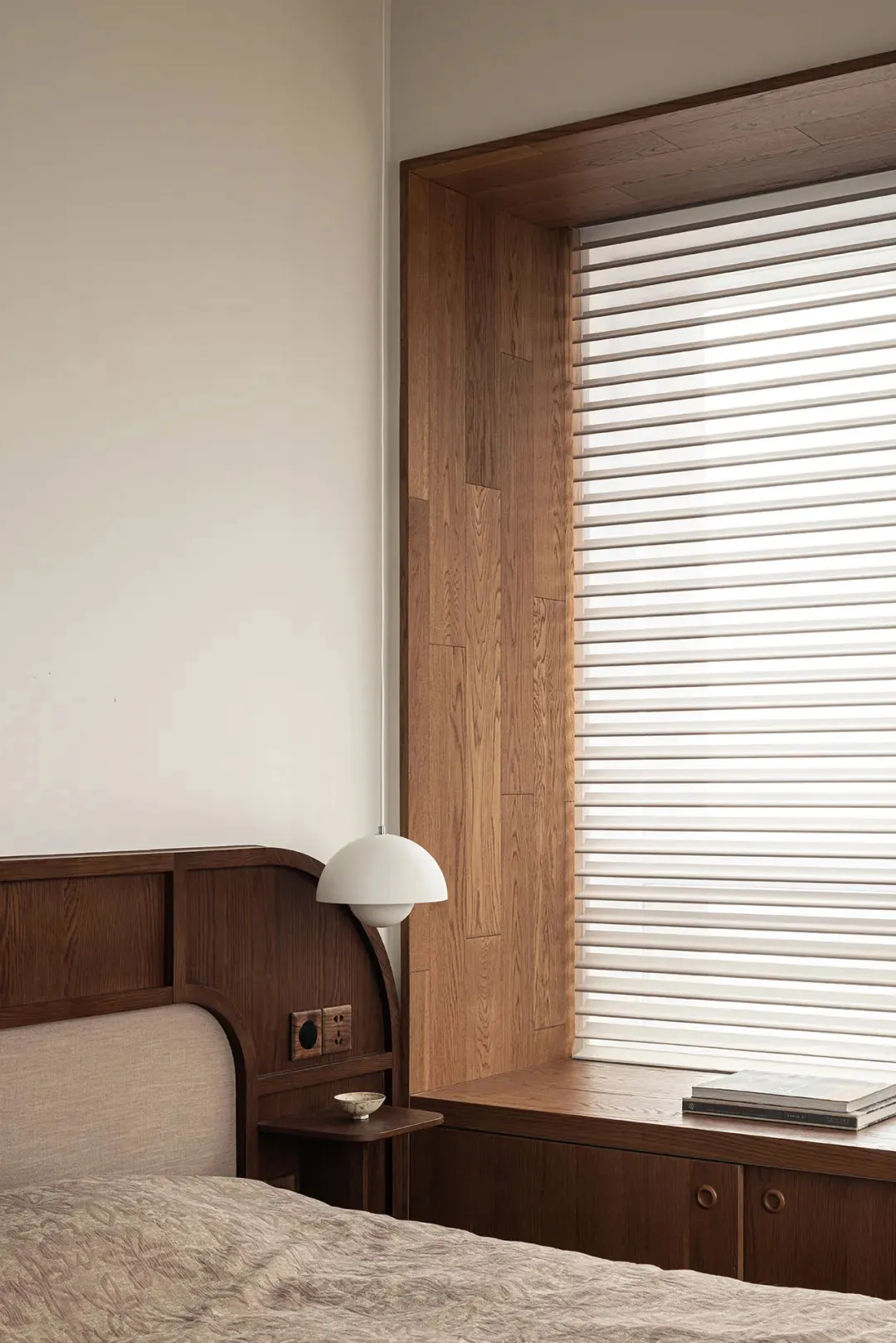 A modern bedroom featuring wooden cabinets and a window seat with blinds.