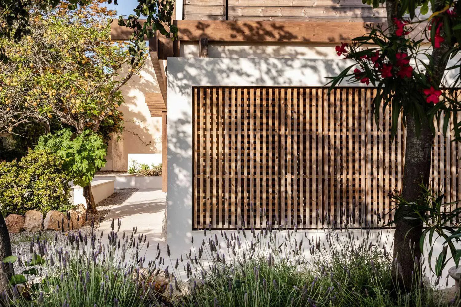 Modern sliding door with a wooden lattice and lavender plants in front of a house with a wooden roof.