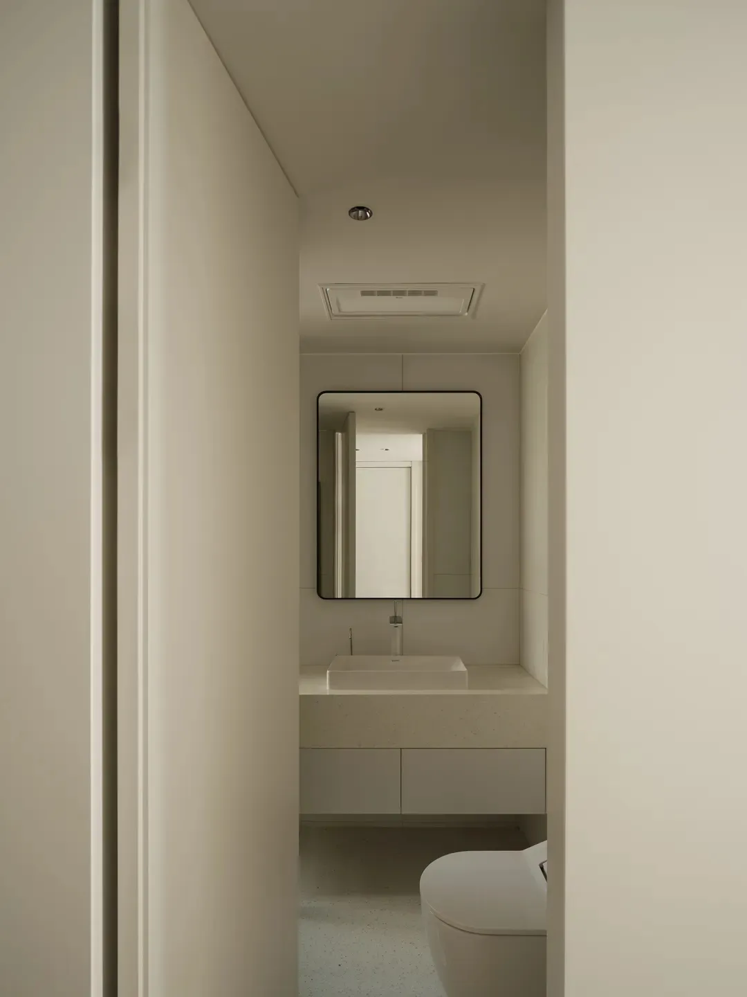 White concrete and terrazzo flooring in a minimalist bathroom