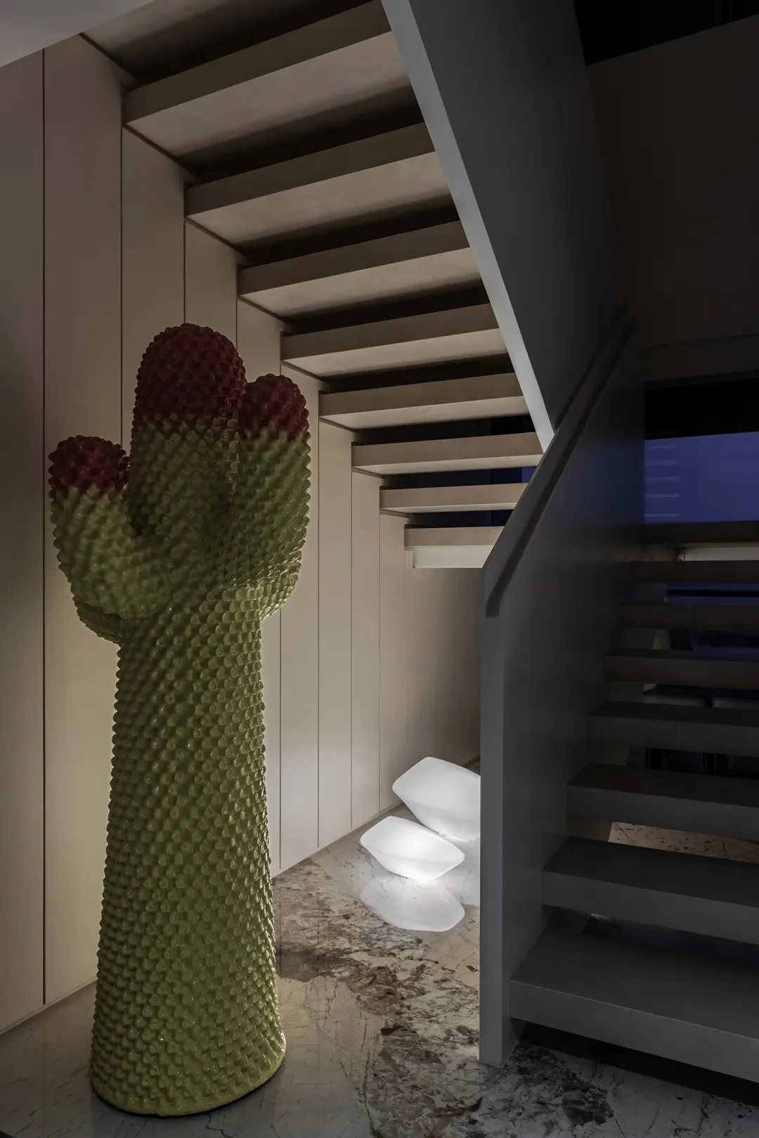 Modern staircase design featuring a realistic cactus sculpture with red flowers and illuminated lighting.