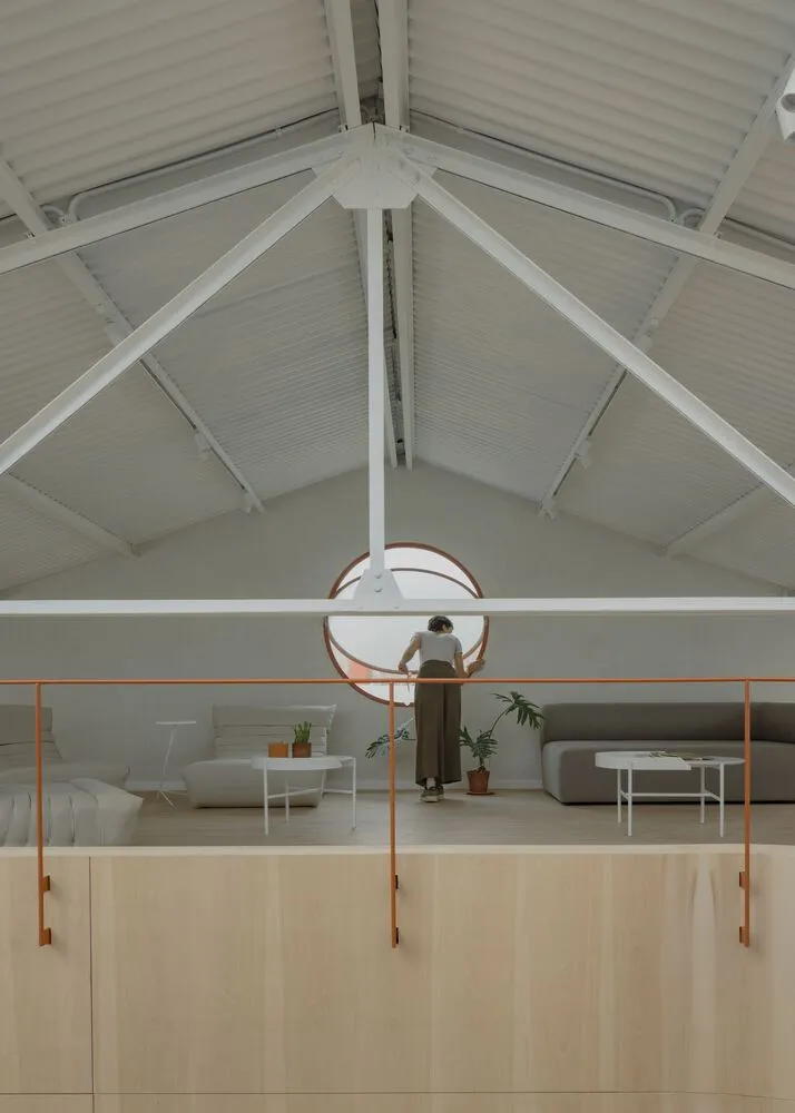 A modern living room featuring wood accents and a high, pitched roof with white beams and a circular window.