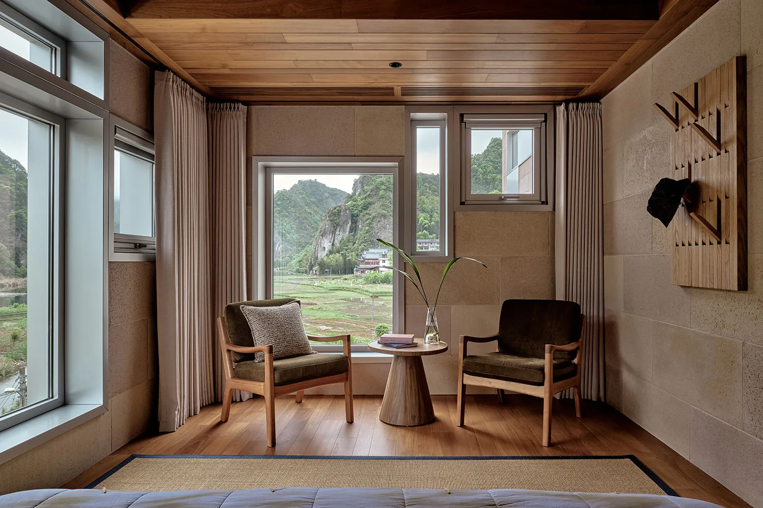 Modern living room with wooden furniture and a view of the mountains through large windows.