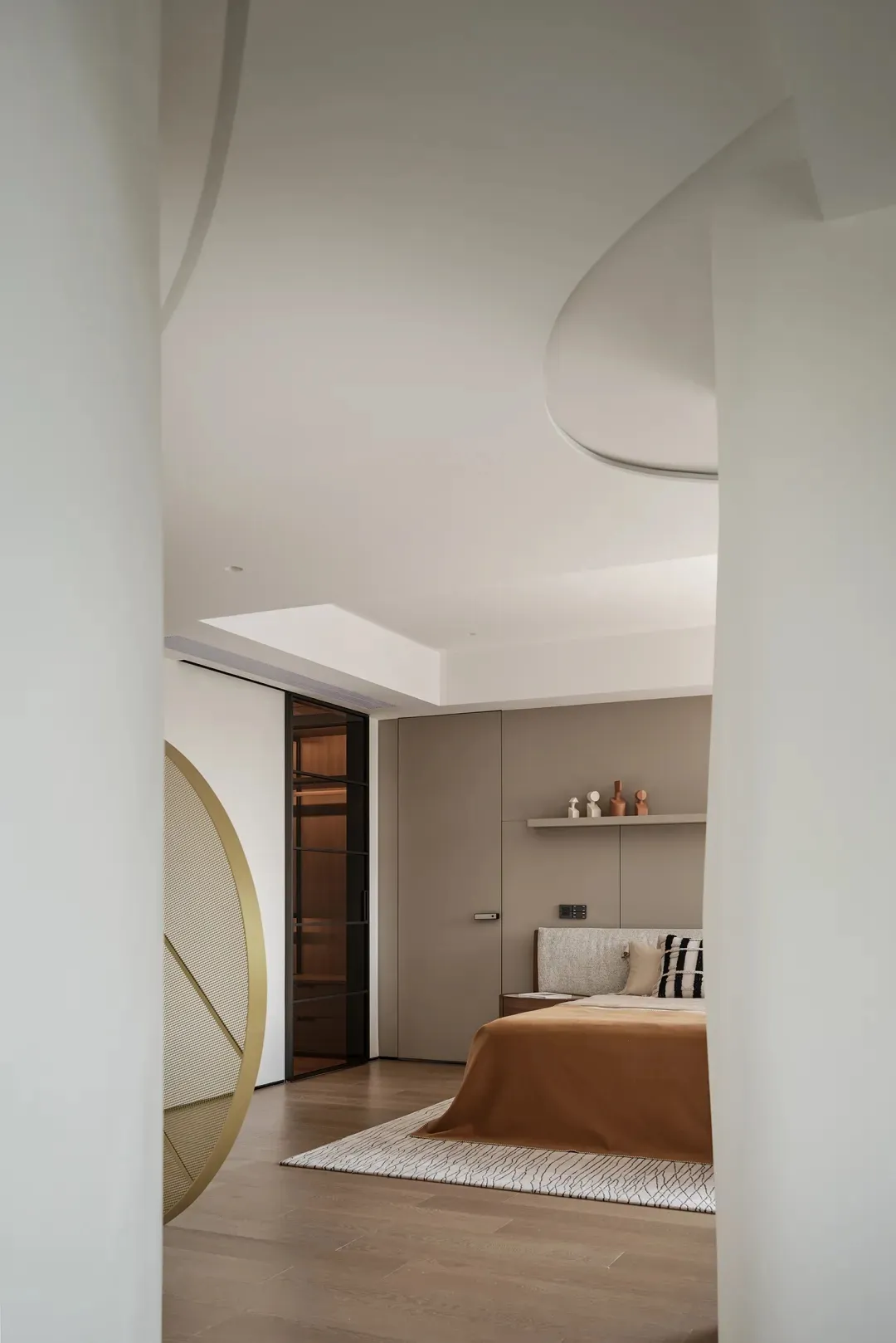 A minimalist bedroom with a beige color scheme and wooden flooring, featuring a bed with a soft bedspread and pillow, and a s