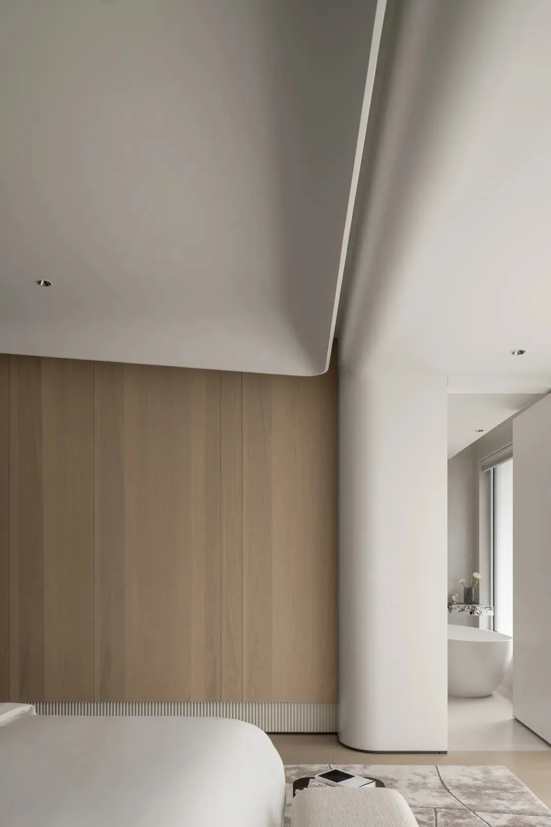 Modern minimalist bedroom featuring a white bed with wooden headboard and white concrete floor.