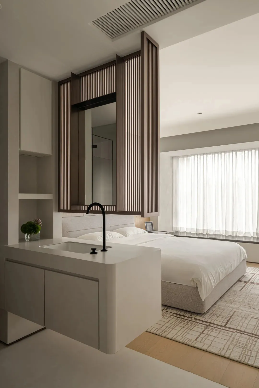 A minimalist bedroom with a wooden panel accent wall and a white bed.