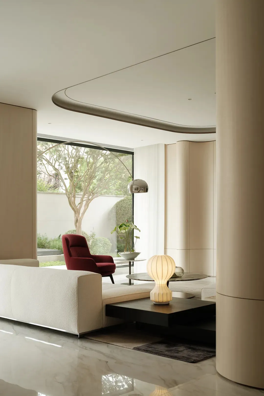 A minimalist modern living room with white furniture, a red armchair, and a glass coffee table.