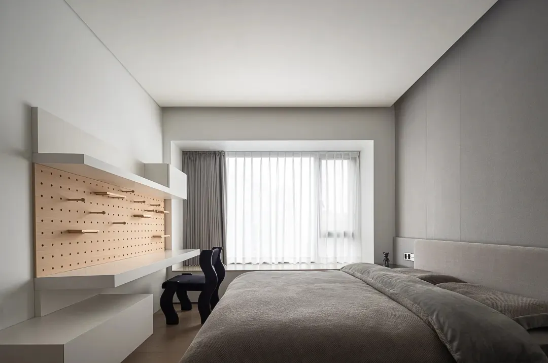 A minimalist bedroom featuring wooden storage units and a large bed with grey bedding.