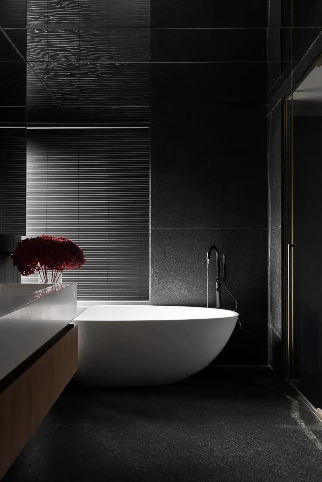 A modern bathroom with a marble bathtub and grey tiles.
