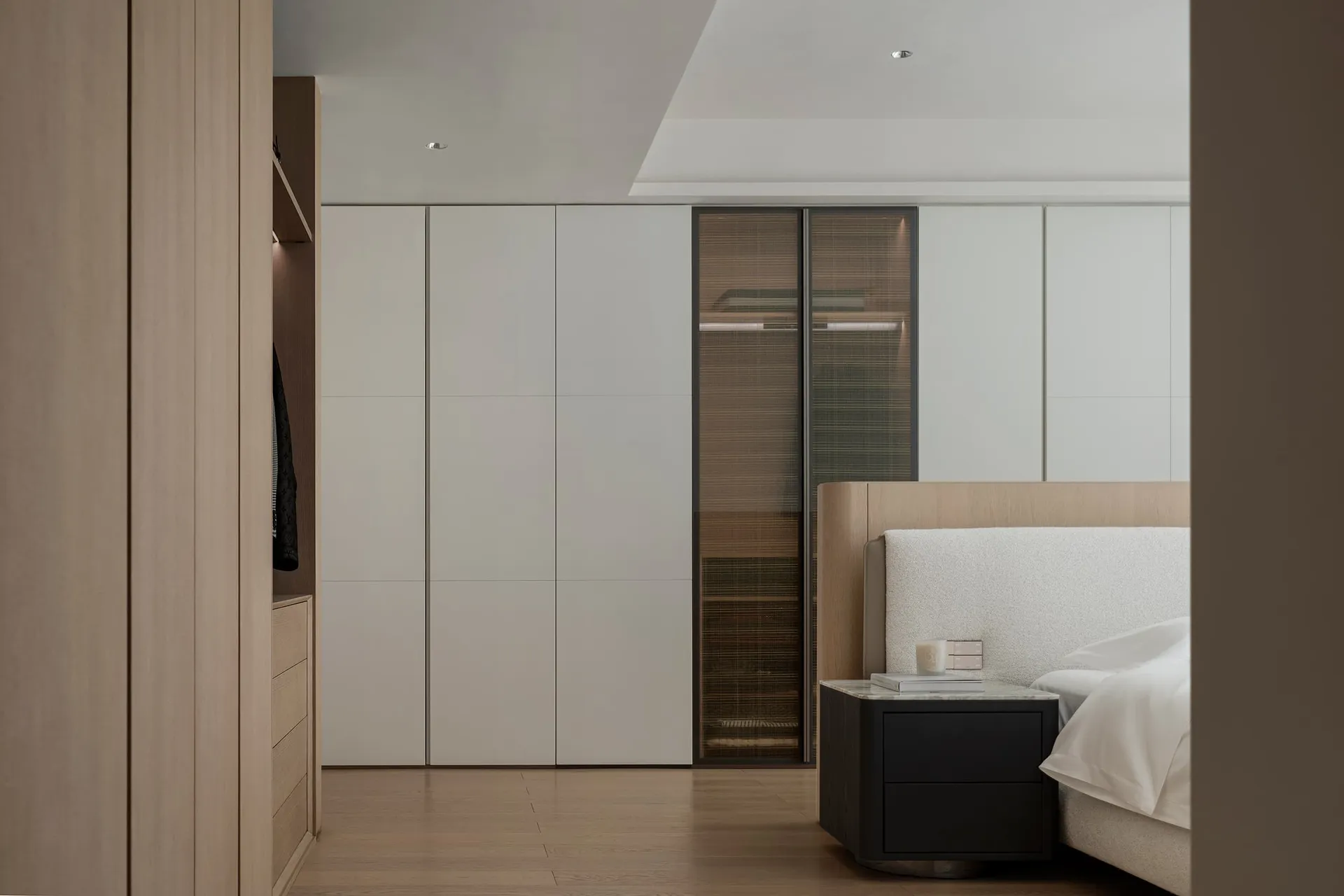 Minimalist bedroom with a wooden bed and glass walls.