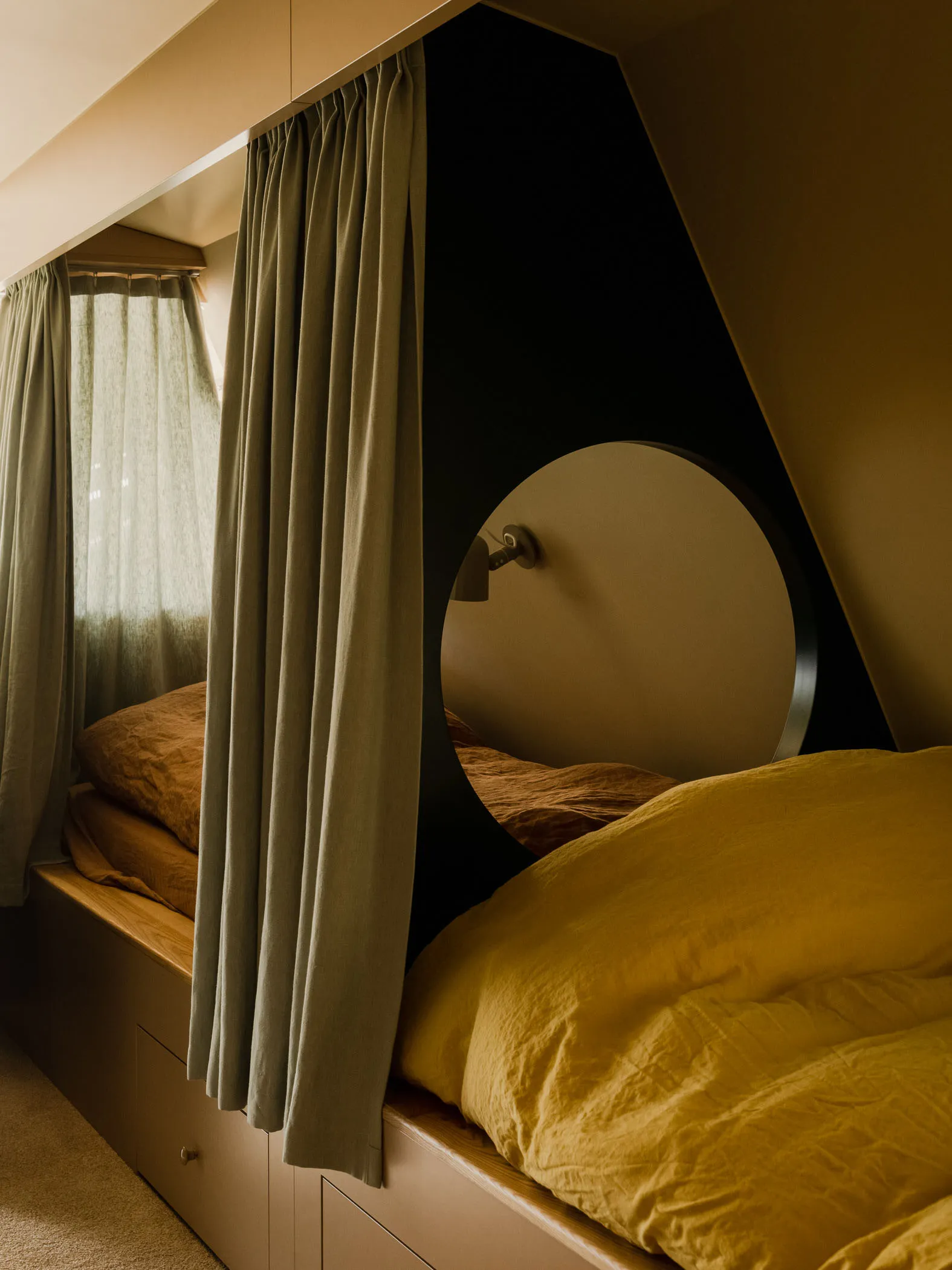 Minimalist bedroom with a bed, curtains, and a circular headboard.