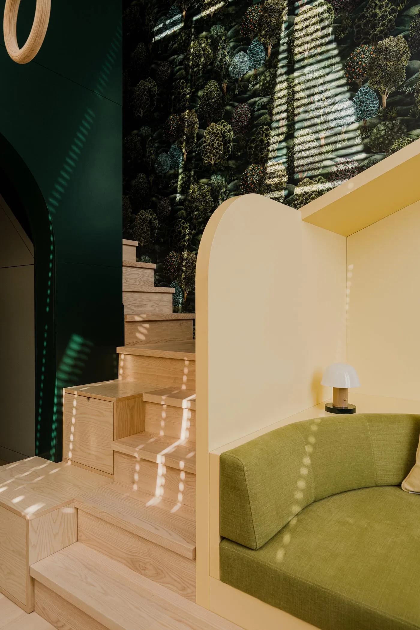 A modern living space featuring a wooden staircase and green upholstered seating.