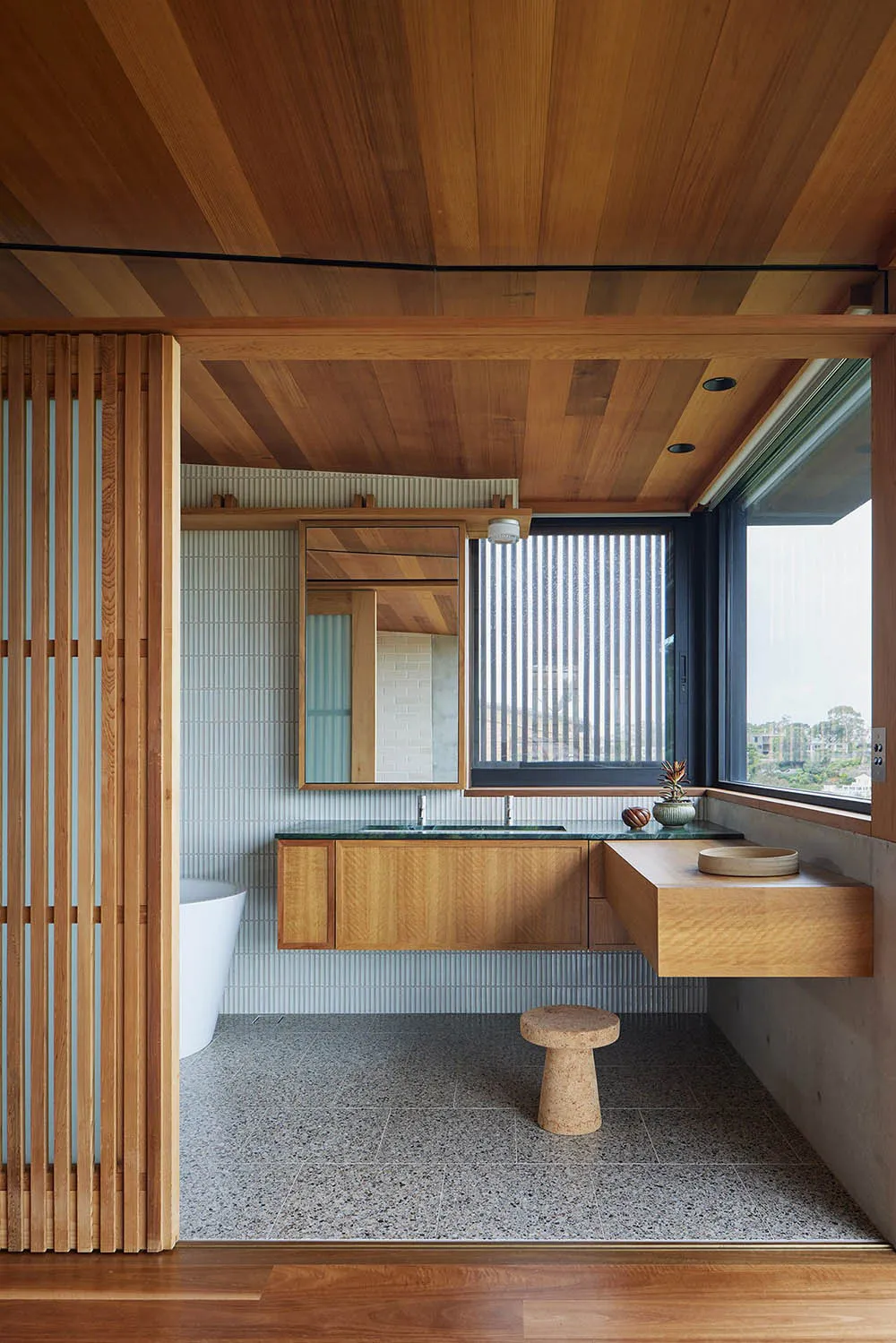 Modern bathroom with wooden walls, floor, and vanity, featuring a frosted window and a stool.