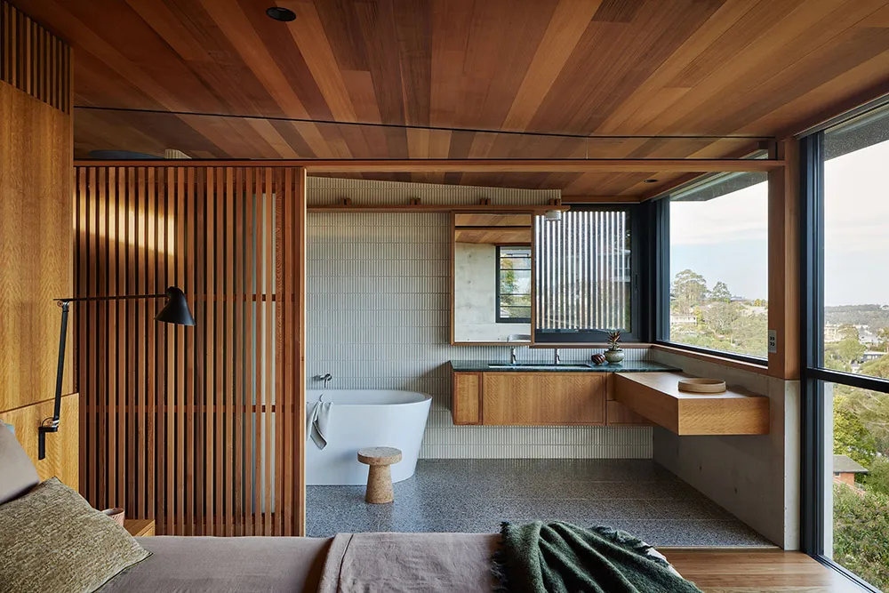 A modern bathroom featuring a wood and concrete design with a white bathtub and a large window.